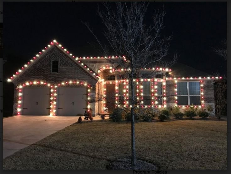 House with red and white holiday lights along the roofline and garage