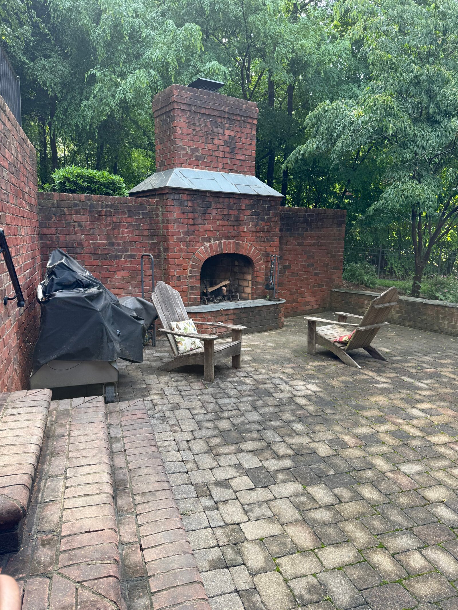 Dirty paver patio with brick fireplace before pressure washing