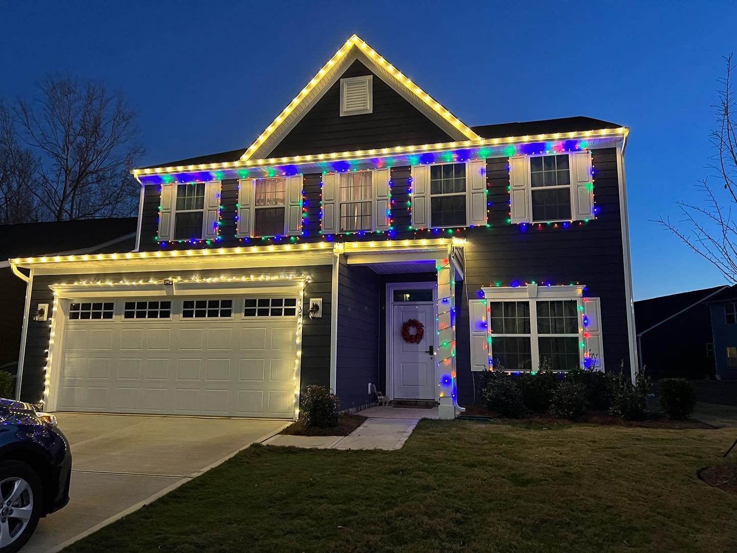 Home with warm white and multicolor holiday lights along the roofline at night