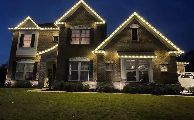 Brick home outlined with warm white roofline lights at night